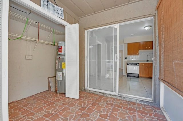 view of exterior entry with electric water heater and sink