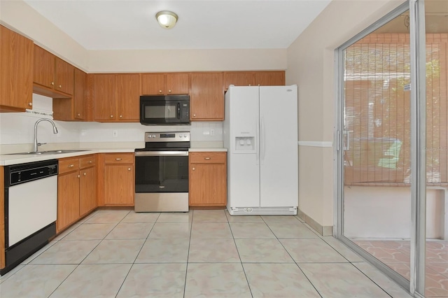 kitchen featuring light tile patterned floors, white appliances, and sink