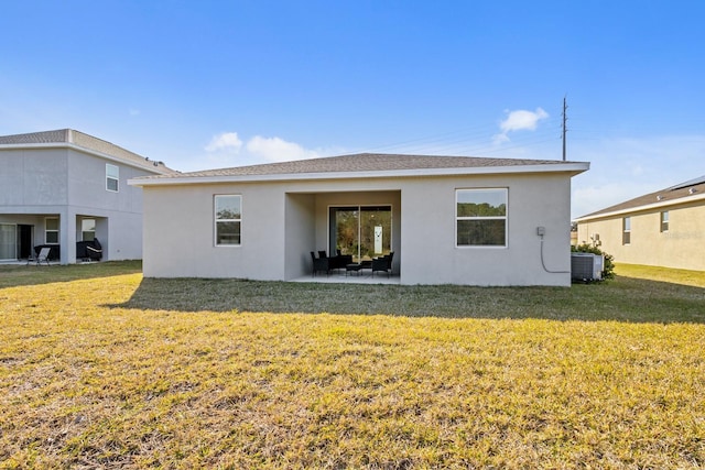 rear view of property with cooling unit, a yard, and a patio