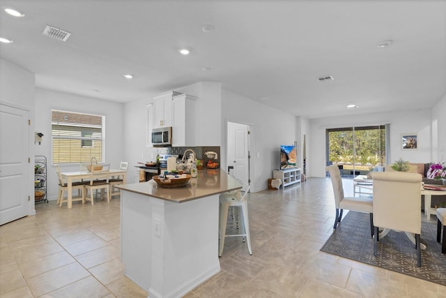 kitchen featuring stainless steel appliances, a wealth of natural light, a breakfast bar area, and white cabinets