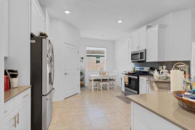 kitchen featuring sink, light tile patterned floors, appliances with stainless steel finishes, white cabinetry, and tasteful backsplash