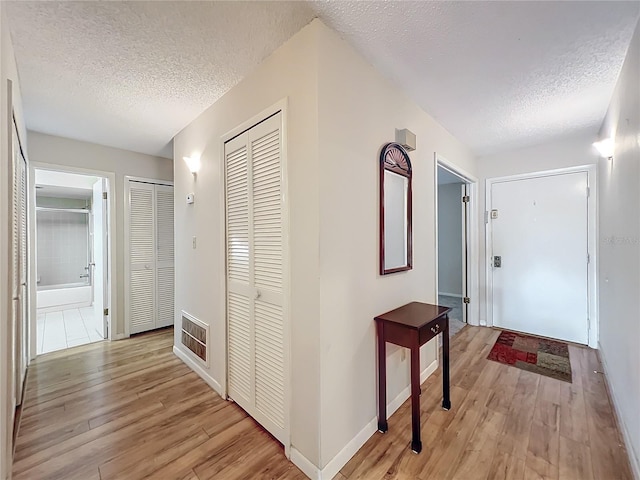 corridor featuring light hardwood / wood-style flooring and a textured ceiling