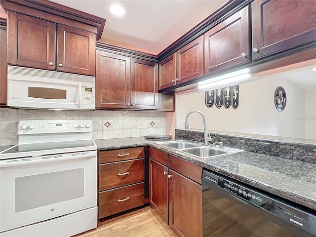 kitchen with white appliances, sink, dark stone countertops, tasteful backsplash, and light hardwood / wood-style floors