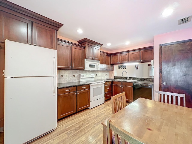 kitchen with white appliances, dark stone counters, sink, light wood-type flooring, and tasteful backsplash