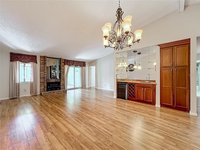 unfurnished living room featuring lofted ceiling, beverage cooler, and light hardwood / wood-style flooring