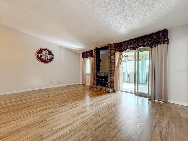 unfurnished living room featuring a fireplace, a textured ceiling, and light hardwood / wood-style flooring