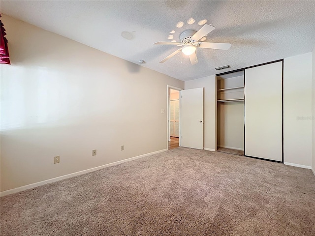 unfurnished bedroom featuring carpet flooring, a textured ceiling, a closet, and ceiling fan