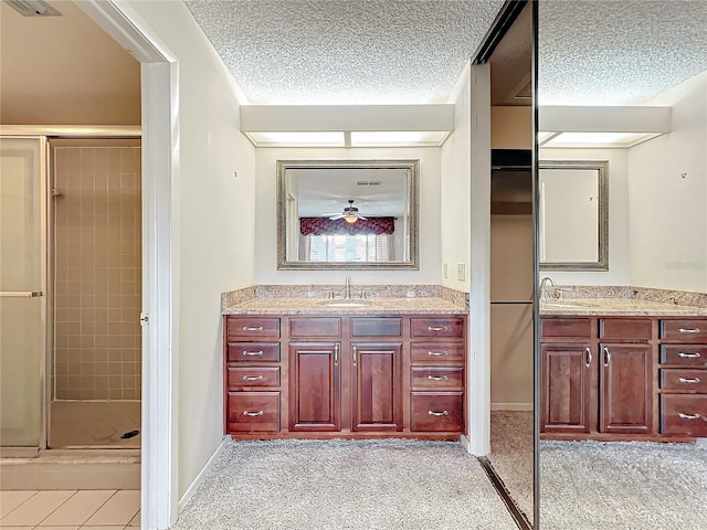 bathroom with vanity, a textured ceiling, and a shower with shower door