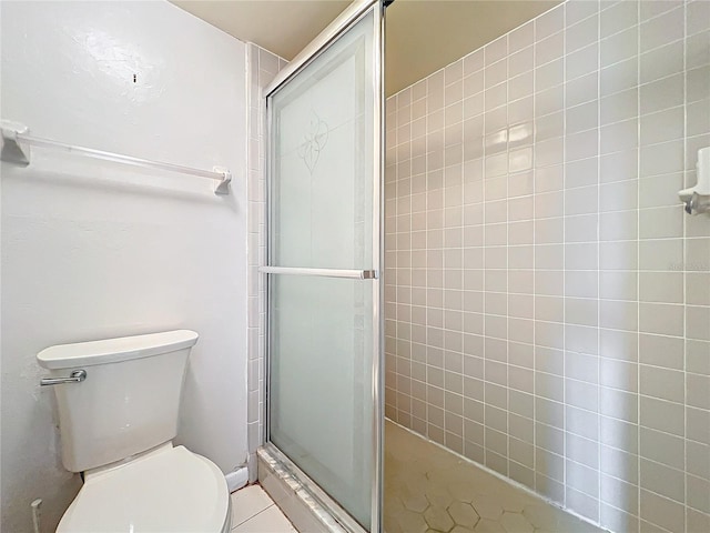 bathroom featuring tile patterned flooring, a shower with shower door, and toilet