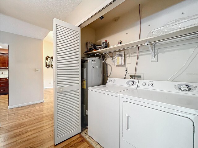 laundry area featuring washer and dryer, a textured ceiling, electric water heater, and light hardwood / wood-style floors