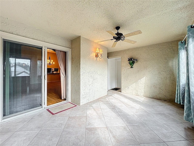 interior space featuring ceiling fan with notable chandelier and a textured ceiling