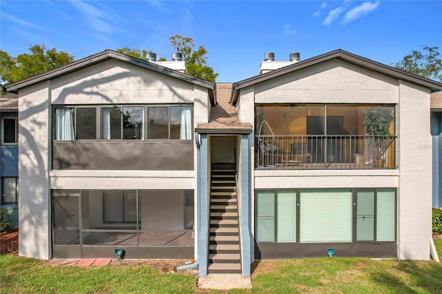 rear view of property featuring a balcony and a lawn