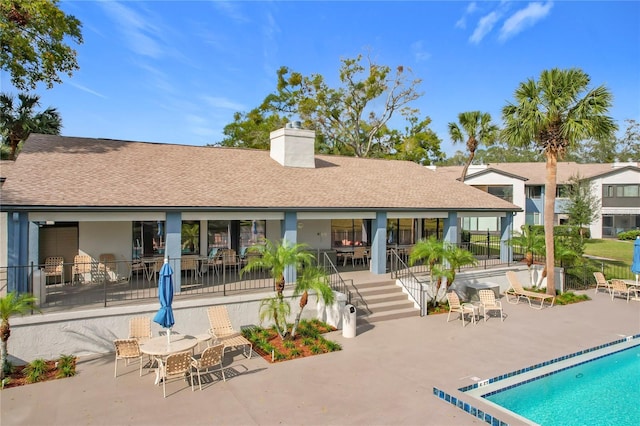 rear view of property featuring a community pool and a patio