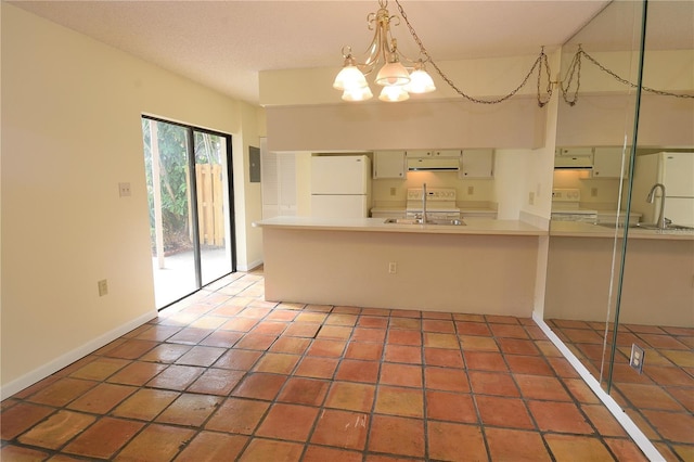 kitchen featuring kitchen peninsula, range, white fridge, and a notable chandelier