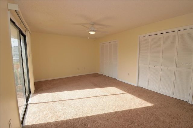 unfurnished bedroom with ceiling fan, carpet floors, and two closets