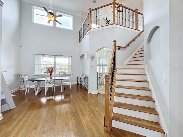 interior space featuring hardwood / wood-style floors, ceiling fan, crown molding, and a high ceiling