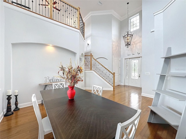 dining room featuring hardwood / wood-style floors, plenty of natural light, a towering ceiling, and crown molding