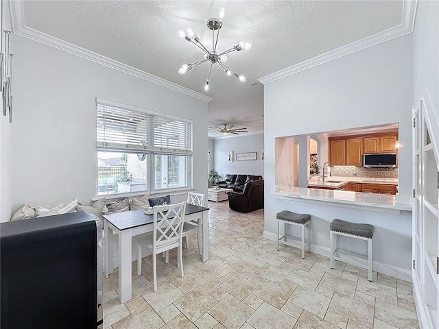 dining space featuring a textured ceiling, sink, ceiling fan with notable chandelier, and ornamental molding