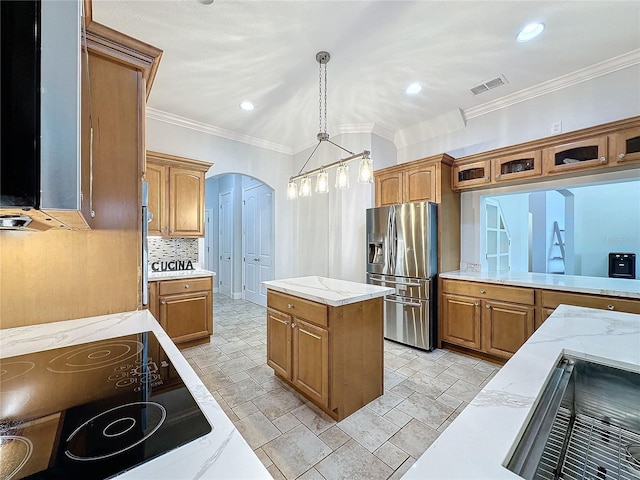 kitchen featuring cooktop, stainless steel fridge, pendant lighting, a kitchen island, and ornamental molding