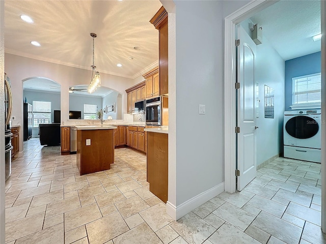 kitchen featuring kitchen peninsula, ornamental molding, stainless steel oven, pendant lighting, and washer / clothes dryer