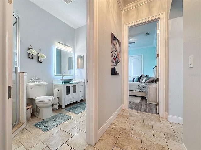 bathroom with an enclosed shower, vanity, toilet, and ornamental molding