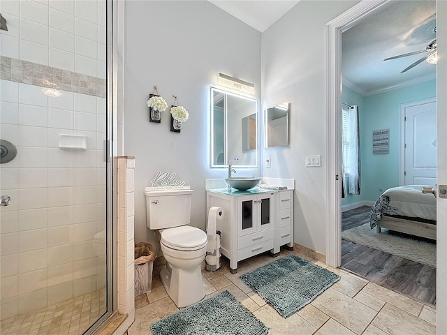 bathroom with vanity, ceiling fan, crown molding, toilet, and a shower with shower door