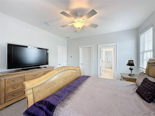 bedroom with ceiling fan, light carpet, and a textured ceiling