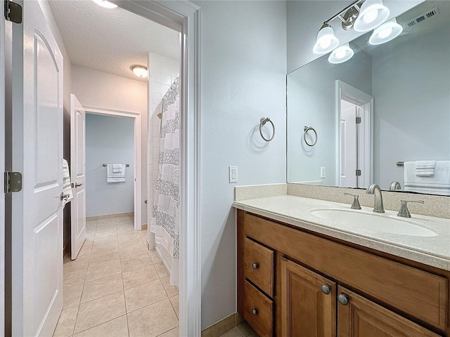 bathroom featuring tile patterned flooring, vanity, and a textured ceiling