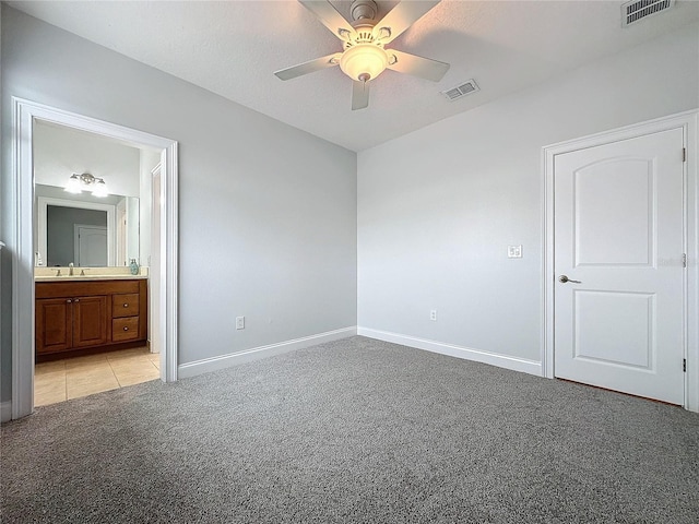 unfurnished bedroom featuring light colored carpet, ensuite bath, ceiling fan, and sink