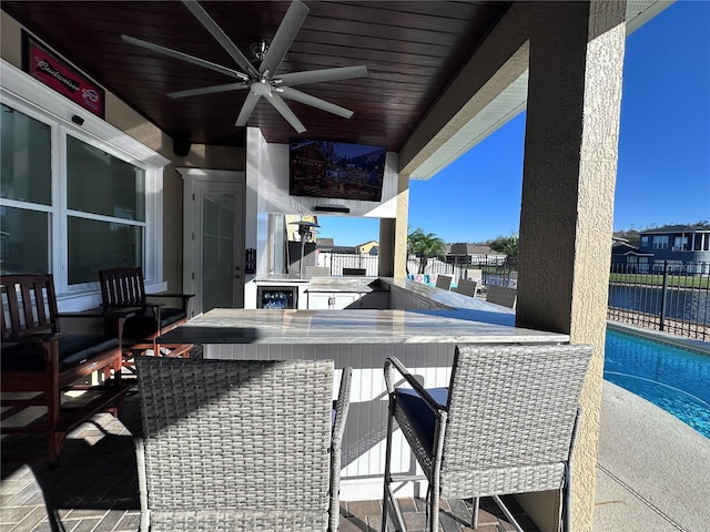 view of patio with a fenced in pool, ceiling fan, a bar, and an outdoor kitchen