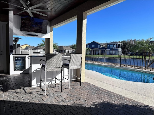 view of pool with ceiling fan and a bar