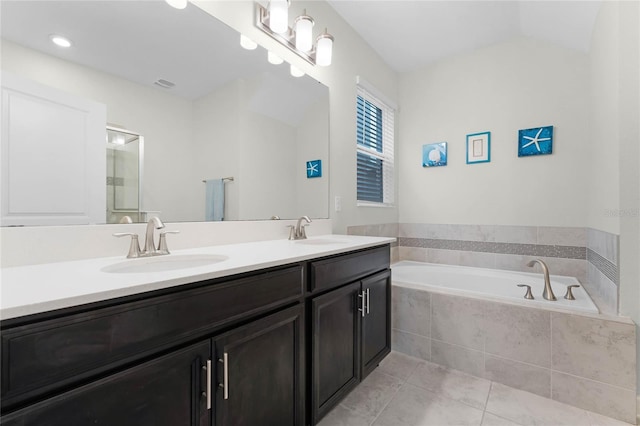 bathroom featuring vanity, tile patterned floors, and tiled tub