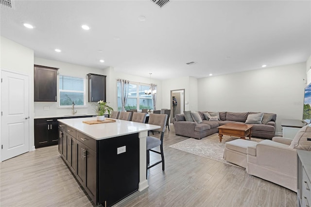 kitchen featuring a kitchen bar, decorative light fixtures, light hardwood / wood-style flooring, a notable chandelier, and a center island