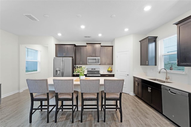 kitchen with a center island, sink, light hardwood / wood-style flooring, dark brown cabinets, and stainless steel appliances