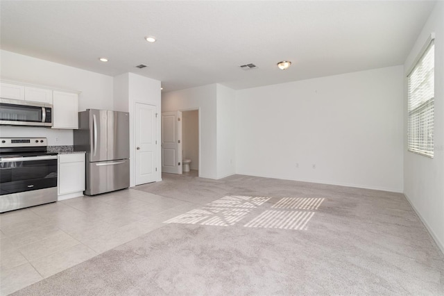 kitchen with white cabinets, light colored carpet, and stainless steel appliances