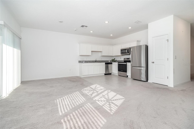 kitchen featuring light colored carpet, white cabinetry, and stainless steel appliances