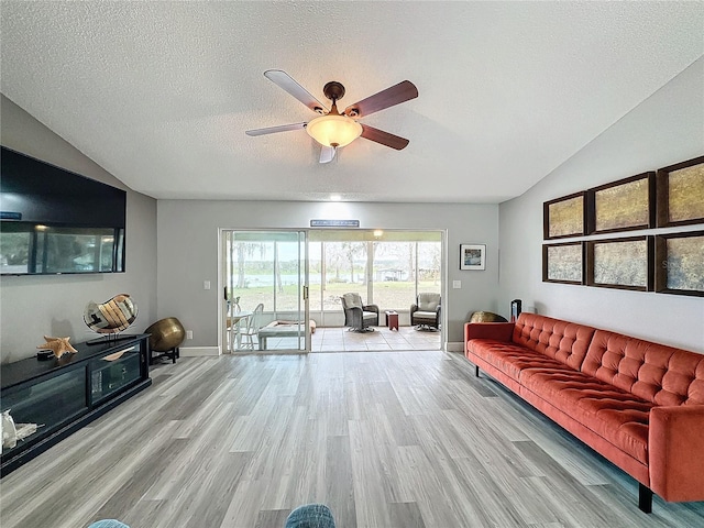 living room with light wood-type flooring, ceiling fan, a textured ceiling, and lofted ceiling