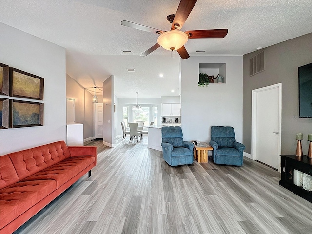 living room featuring light hardwood / wood-style floors, a textured ceiling, and ceiling fan