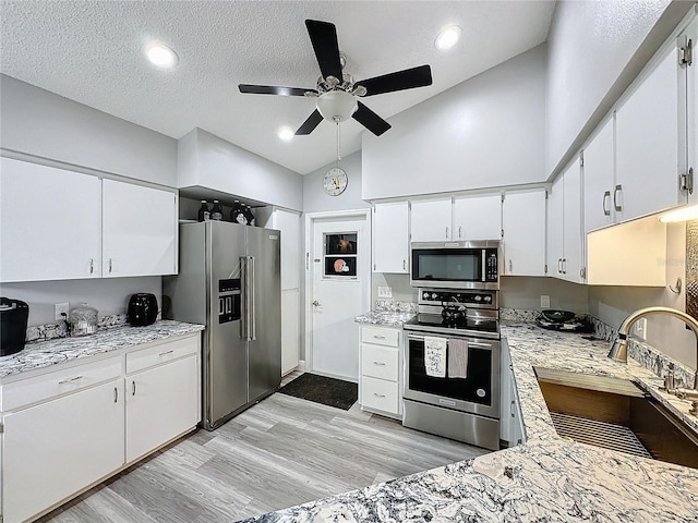 kitchen featuring a textured ceiling, white cabinets, appliances with stainless steel finishes, light hardwood / wood-style floors, and sink