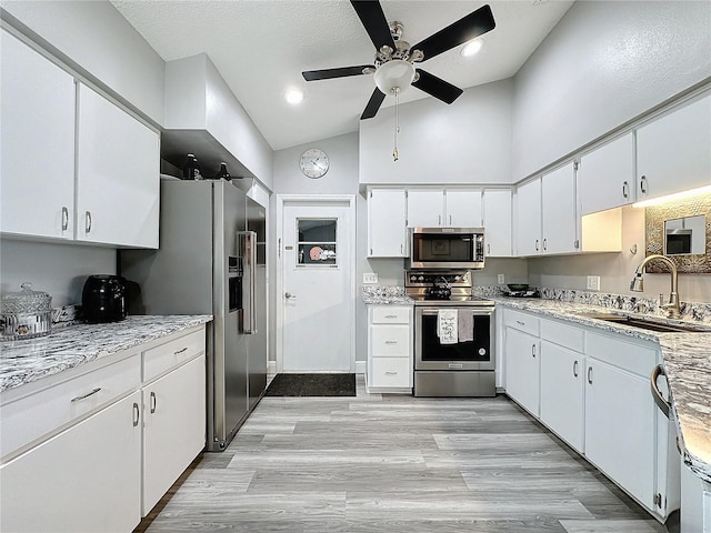 kitchen featuring sink, white cabinetry, high vaulted ceiling, light hardwood / wood-style floors, and stainless steel appliances