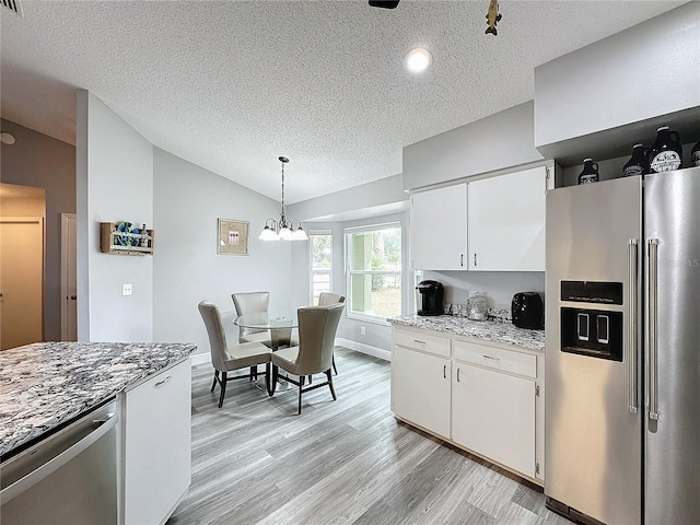 kitchen with vaulted ceiling, hanging light fixtures, appliances with stainless steel finishes, white cabinets, and light stone countertops