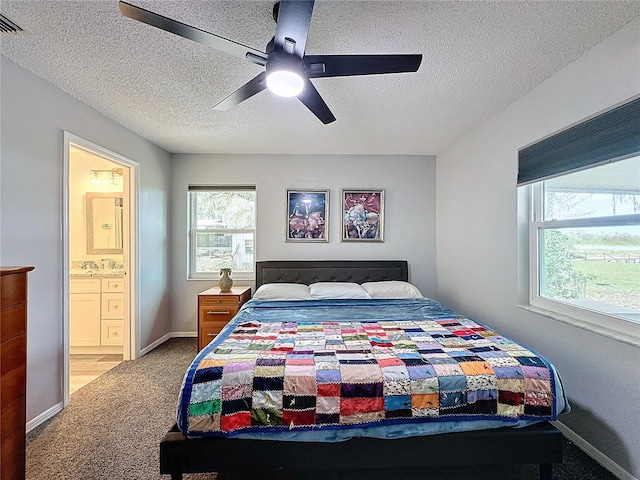 bedroom featuring carpet flooring, multiple windows, ensuite bathroom, and ceiling fan