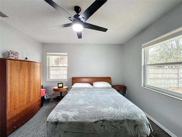 carpeted bedroom with multiple windows, a textured ceiling, and ceiling fan