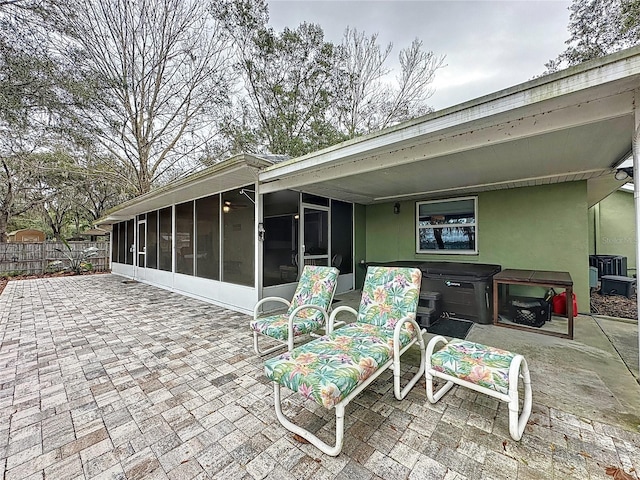 view of patio / terrace with a hot tub and a sunroom