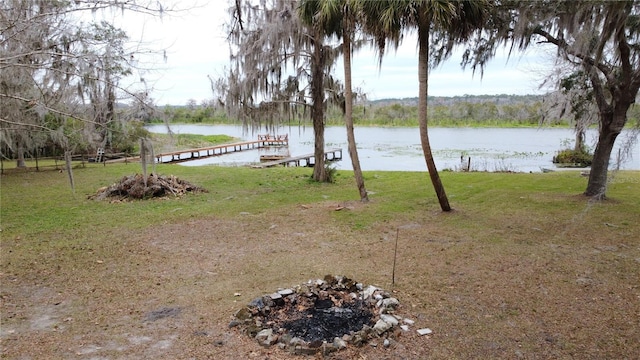 view of yard with an outdoor fire pit, a dock, and a water view