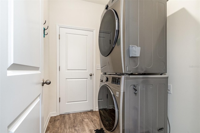 washroom featuring hardwood / wood-style floors and stacked washer / drying machine