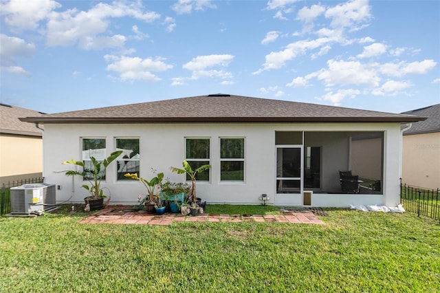 rear view of house featuring a yard, central AC unit, and a sunroom