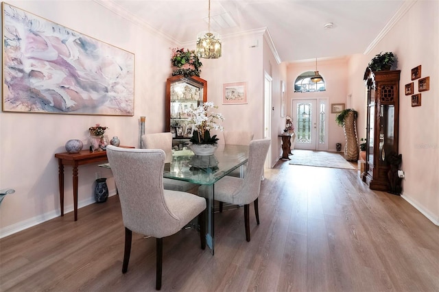 dining space featuring hardwood / wood-style floors, crown molding, and an inviting chandelier