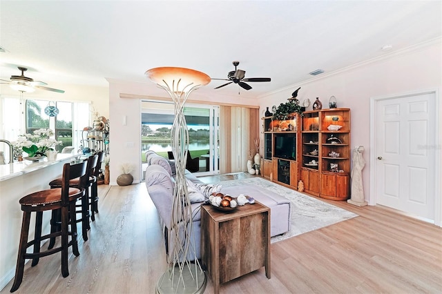 living room featuring ceiling fan, crown molding, and light hardwood / wood-style flooring