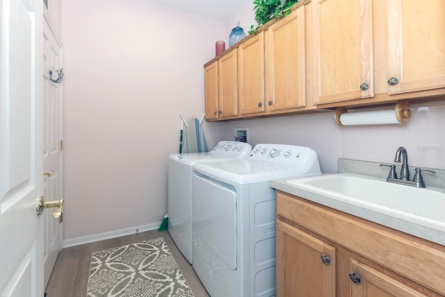 laundry area with hardwood / wood-style flooring, washer and dryer, cabinets, and sink